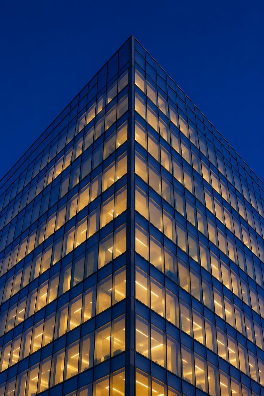 Modern office tower lit at dusk
